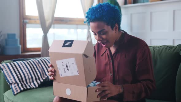 Young Overjoyed African American Woman Unpacks Box and Screams with Happiness alt