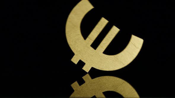 Golden Euro symbol falls on a black background