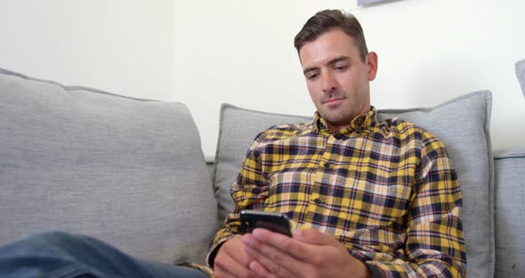 Young man using mobile phone in living room at home 
