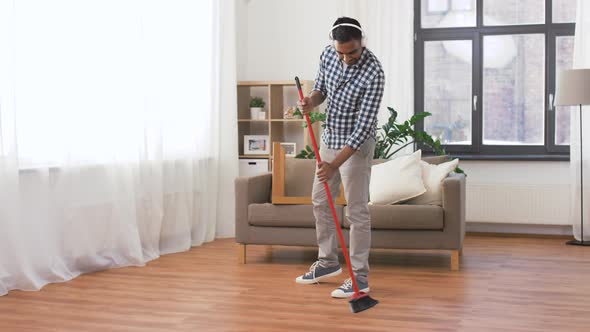 Man in Headphones with Broom Cleaning at Home 53 alt