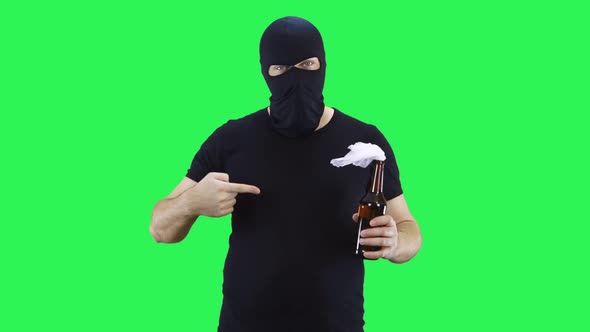 A man in a black mask holds in his hand a bottle of Molotov cocktail and points