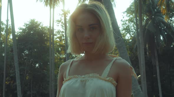 Young Blonde Standing Contemplating Tropical Rainforest Sunset Light Coming From Above alt