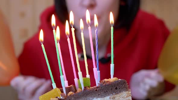 Happy Female Blows Out Candles on a Birthday Piece of Cake alt