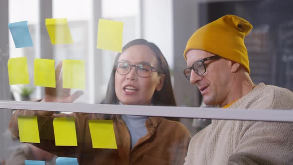 Asian Woman and Middle-Aged Man Brainstorming Ideas in Office alt