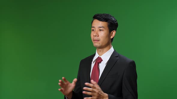 Asian Businessman In Suit Jacket Standing And Presenting Something On Green Screen Background alt