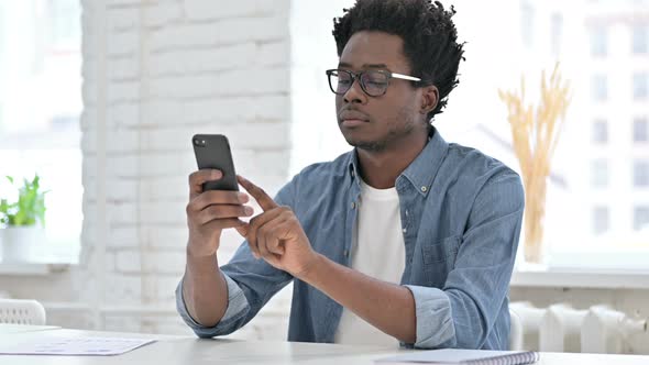 Young African Man Scrolling on Smartphone  alt