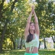 Young European Woman Sportswear Purple Mat Practicing Yoga Pose Park Green Lush Meadow City Park - VideoHive Item for Sale