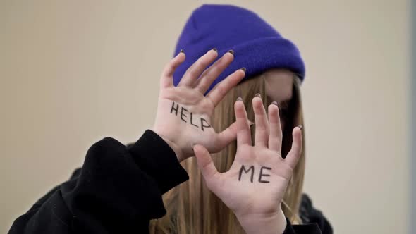 Teenage Girl Covers Her Face with Her Palms with the Inscription HELP ME