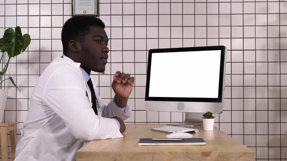 Bored African Doctor Waiting for Something By the Computer Screen alt