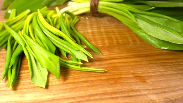 Wild garlic leaves on a wooden cutting board. alt
