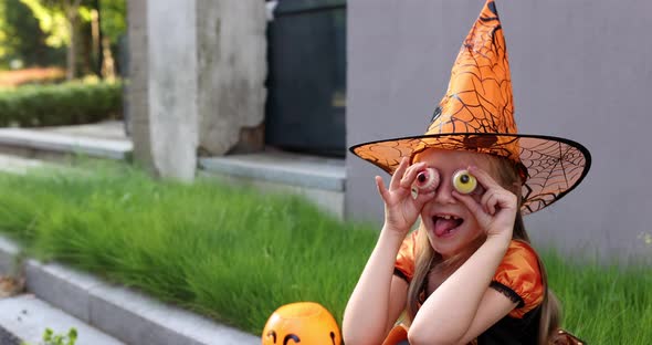 Cute Little Caucasian Girl with Blonde Hair Seven Years Old in Costume of Witch with Hat and Black alt