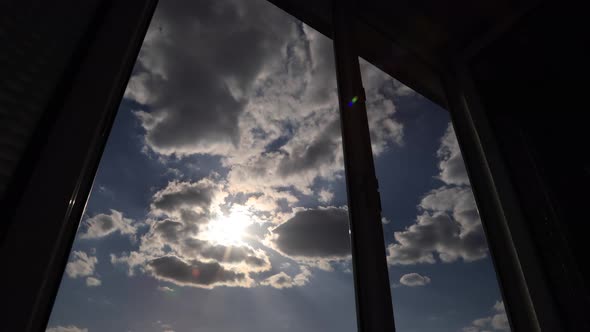 Amazing time lapse: the sun appears in window on the background with fluffy clouds