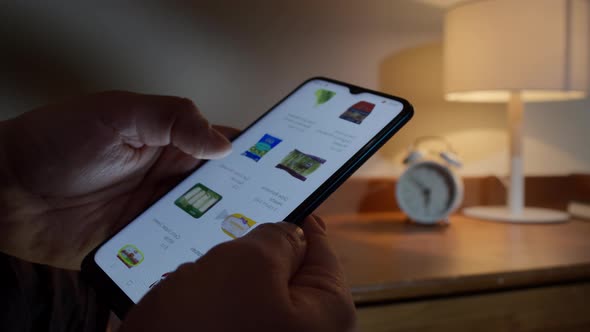 Man Holds a Mobile Phone and Scrolls the Web Page of a Grocery Store alt