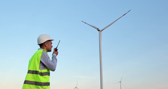An engineer with a walkie-talkie near the wind generator.