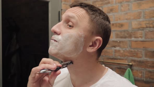 A Man Puffs Out His Cheeks While Shaving