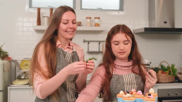 Mother and daughter enjoy to decorate the topping of cupcake in kitchen of happy family concept