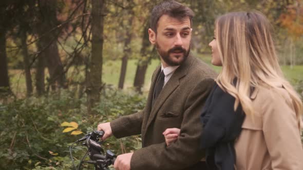 Handsome young couple in the autumn park with electrical bicycle