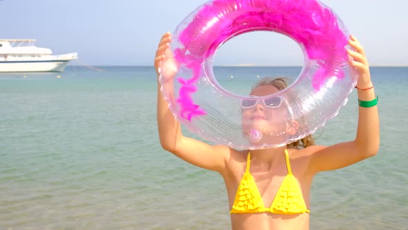 A Child on the Beach Holds a Swimming Circle alt