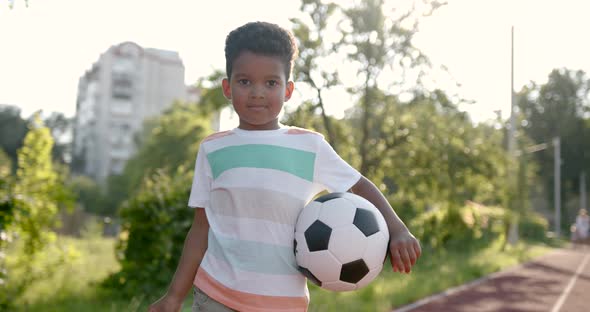 Cute Black Boy Holding a Soccer Ball at Playground alt
