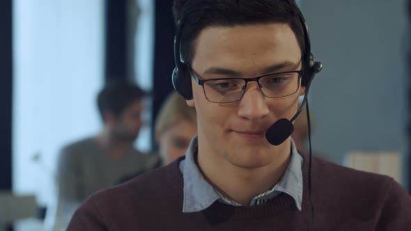 Young Man Working at a Computer in a Call Centre Smiling alt