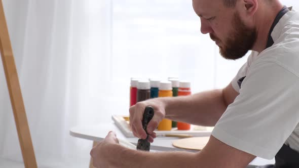 Male Artist Paints a Picture with Oil Paints Artist While Working in the Studio alt