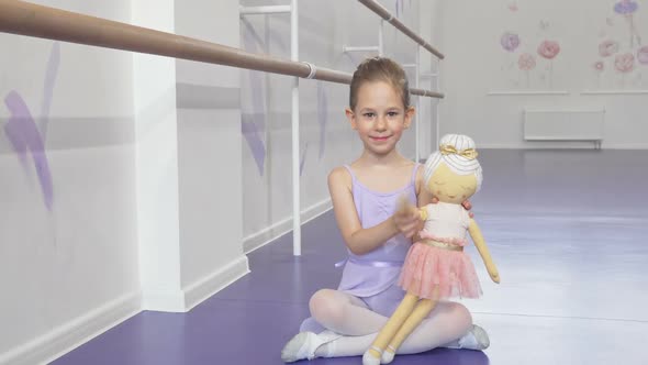 Full Length Shot of a Lovely Little Ballerina Waving To the Camera Playing with a Doll alt