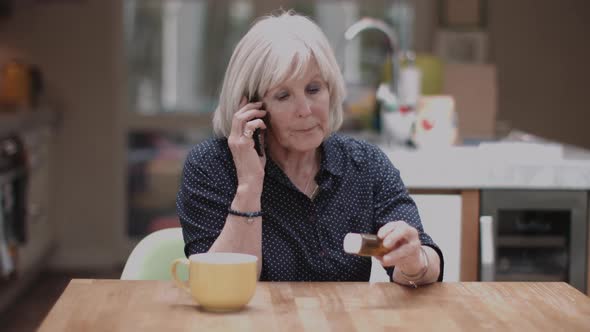 Senior Adult woman calling doctor and holding medicine at home