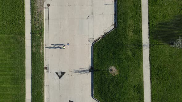 Top down view of cracked street cement. Green grass separating parallel sidewalks and street.