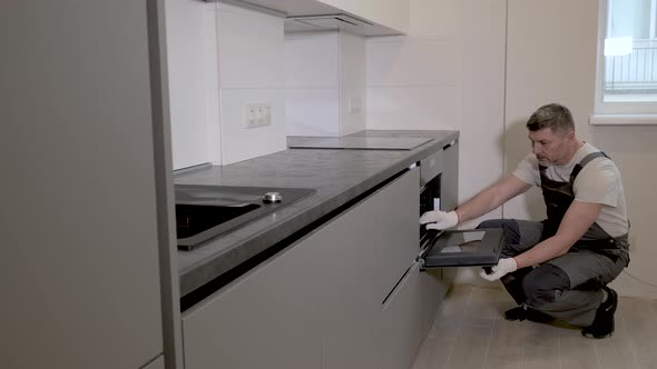 The Builder Checks Quality of Installation of the Kitchen Furniture Structure alt