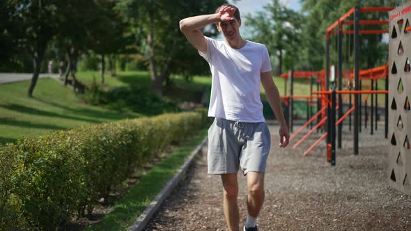 Perspiring Young Sportsman Walking Outdoors in Slow Motion After Training alt