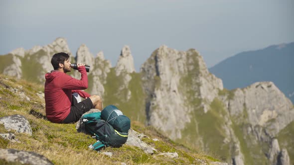 Person Drinking Water on Top of the Mountain with a Scenic View During Autumn 
