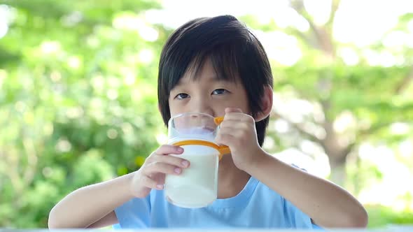 Cute Asian Child With A Glass Of Milk And Licking Lips alt