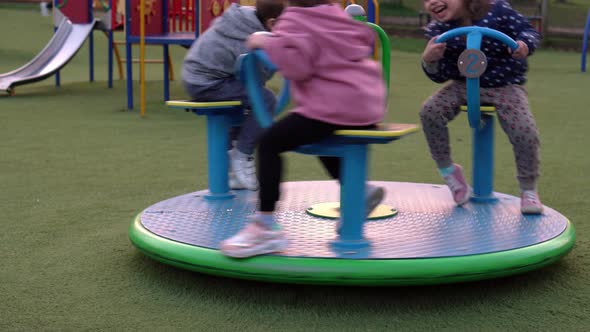 Three Little Happy Children Having Fun Spinning on Merrygoround alt