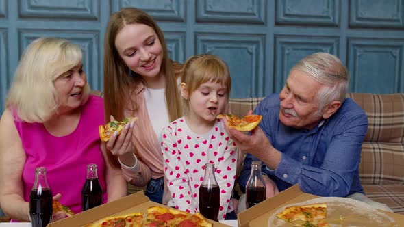 Multigenerational Family Having Lunch Party Feeding Child Girl with Pizza Laughing Enjoying Meal alt