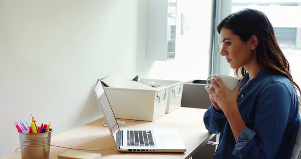 Female executive using laptop white having coffee alt