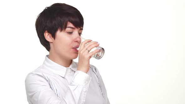 Confident Caucasian Lady Looking at Camera and Drinking Water From Glass Isolated Over White alt
