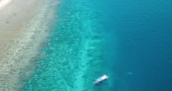 Longtail dive boat in tropical climate over coral reef, Indonesia, aerial view