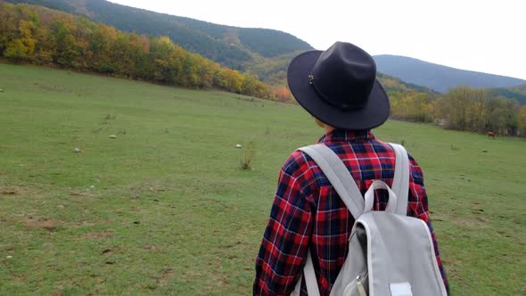 Stylish Hipster Woman with Backpack Walking at Amazing Autumn Field alt