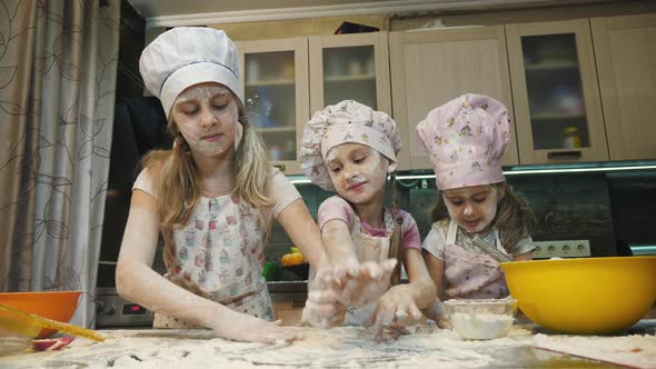 Girls playing with flour on the kitchen table alt