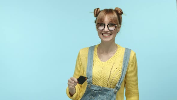 Young Happy Woman in Hipster Glasses Bragging with Plastic Credit Card Smiling Pleased Kissing It