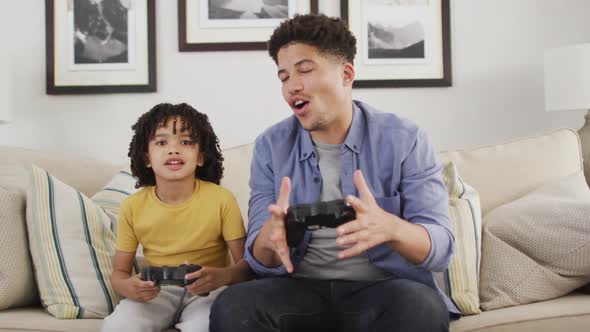 Happy biracial man and his son playing video games alt
