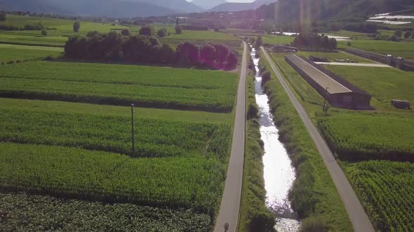Aerial view of a young man riding a bicycle in Sugana Valley, Italy with camera tilting down as bike alt