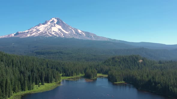 Aerial drone flying above Trillium Lake toward snow covered Mt. Hood in summer time. alt