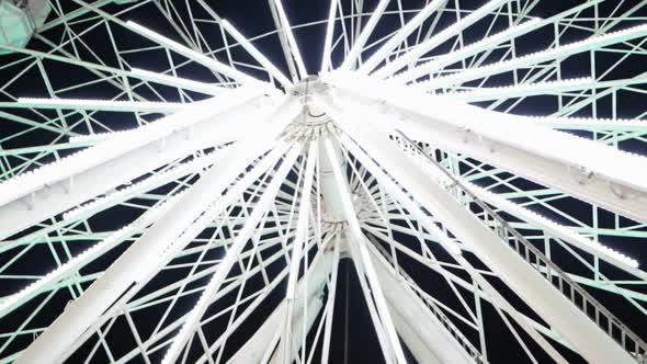 Bottom View of Ferris Wheel Spinning and Flashing White Lights at Night alt