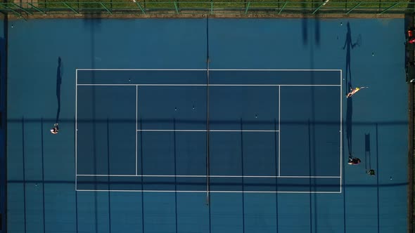 Top view of a blue tennis court with players in training