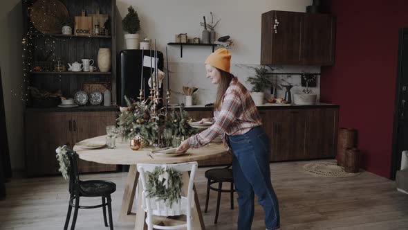 Plump Woman Serves and Arranges the Plates on the Festive Christmas Table alt