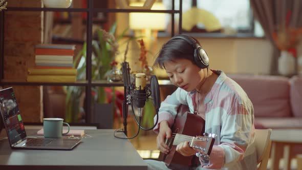 Asian Woman Playing Guitar and Recording Song in Home Studio alt