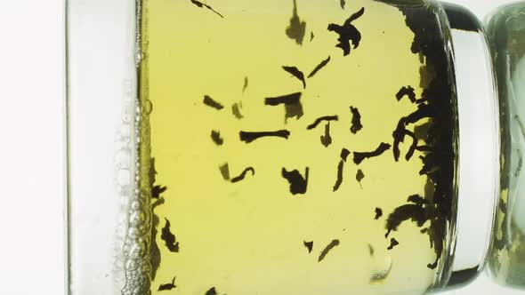 Vertical Video Black Tea Particles Pouring Into Glass Transparent Mug and Filled with Boiling Water