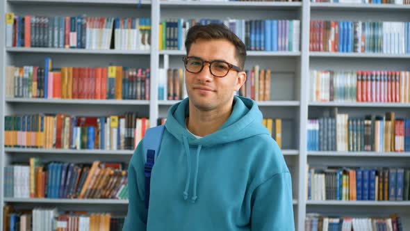 A Young Millennial Student Looking at the Camera and Smiling While Standing in a Public Library