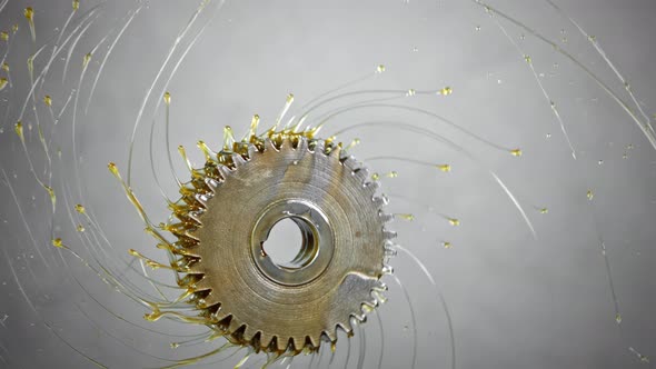 Super Slow Motion Shot of Rotating and Splashing Metal Cogwheel on Grey Background at 1000 Fps alt